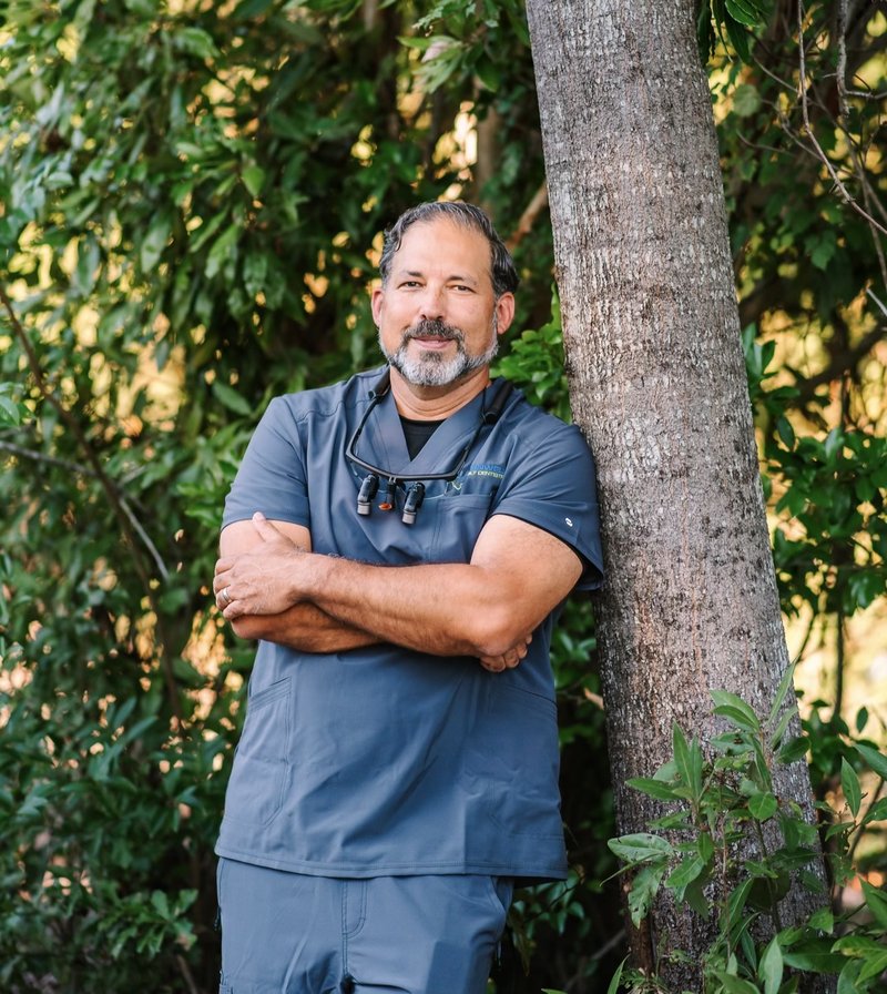 Barnwell Family Dentistry | Dentist in scrubs leaning against a tree